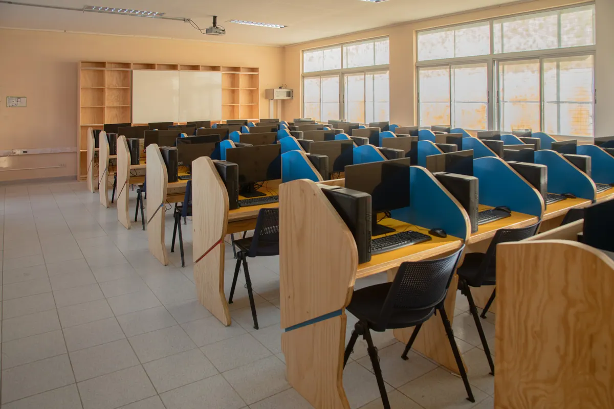 Hileras de puestos con divisiones azules en una sala de informática de 40 puestos